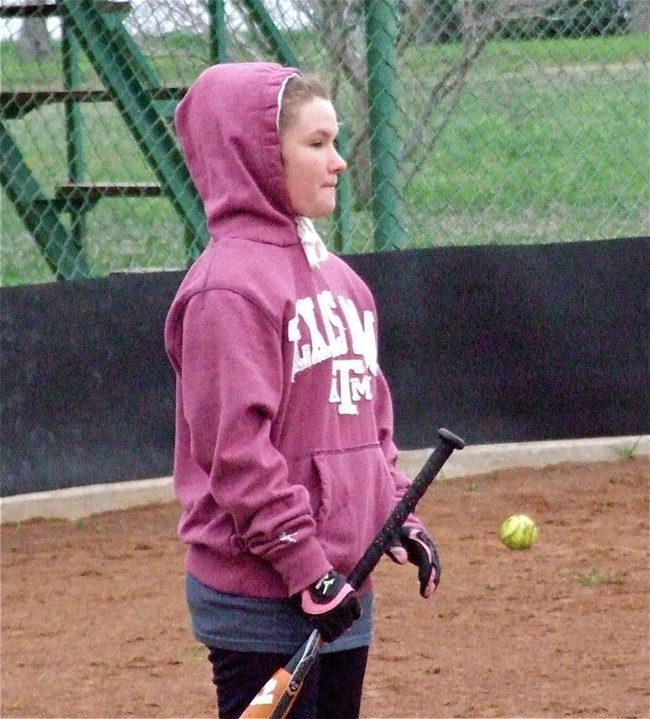 Image: Freshman Lady Gladiator Tara Wallis tries to stay warm before taking her turn at the plate.