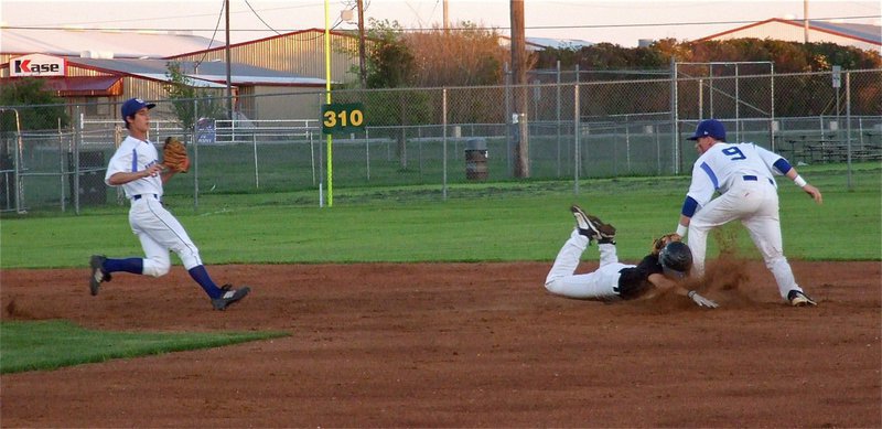 Image: Reid Jacinto gets caught in a run down but beats the throw to second base and slides under the tag.