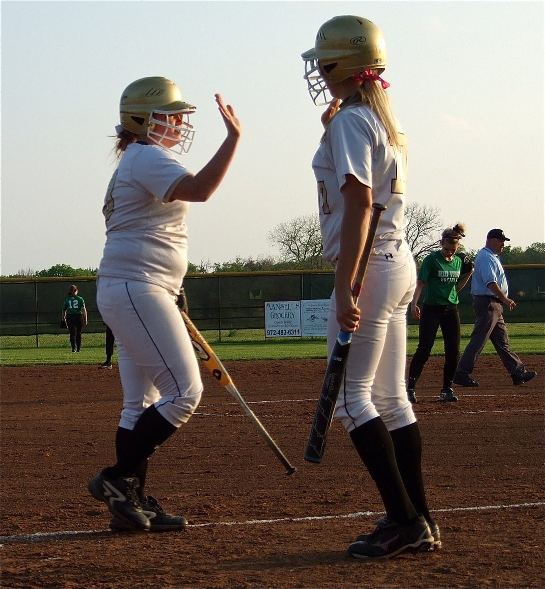 Image: Katie Byers(13) and teammate Megan Richards(17) high-five after Byers crossed home plate.