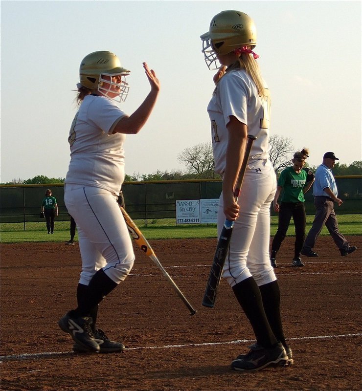 Image: Katie Byers(13) and teammate Megan Richards(17) high-five after Byers crossed home plate.