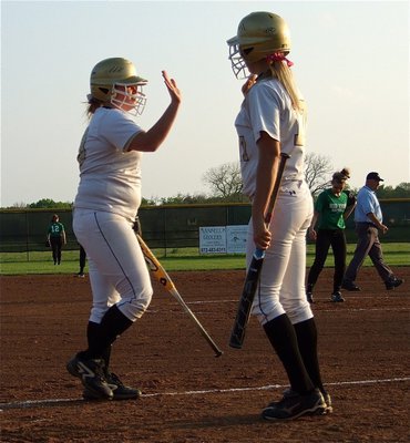 Image: Katie Byers(13) and teammate Megan Richards(17) high-five after Byers crossed home plate.
