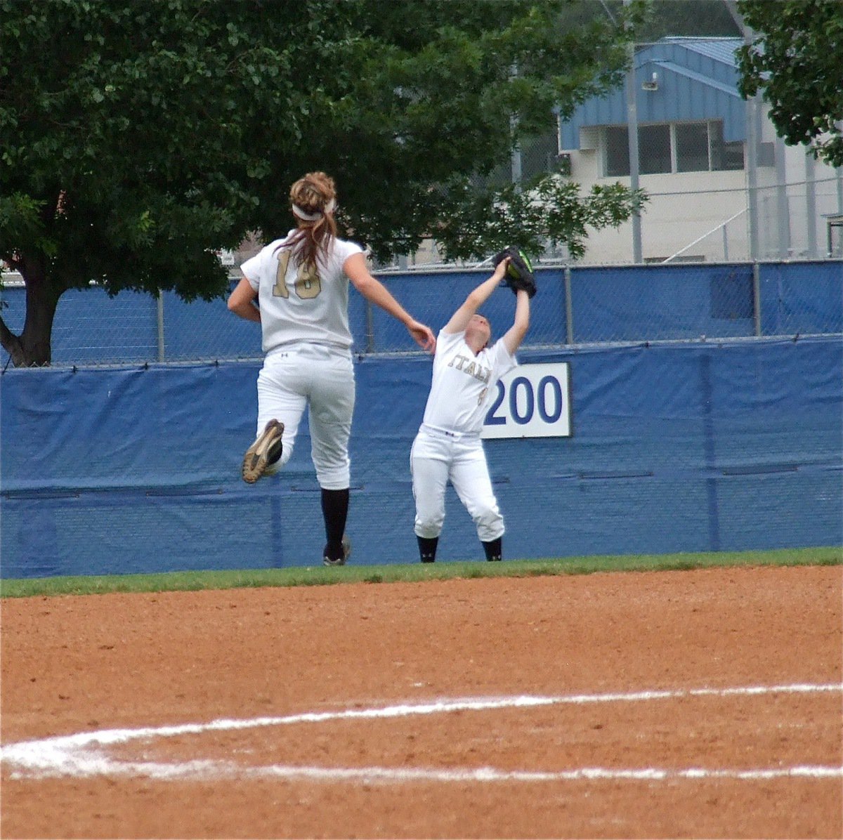 Image: Bailey Bumpus(18) tracks the ball as left fielder Tara Wallis(8) makes the grab for the Lady Gladiators.
