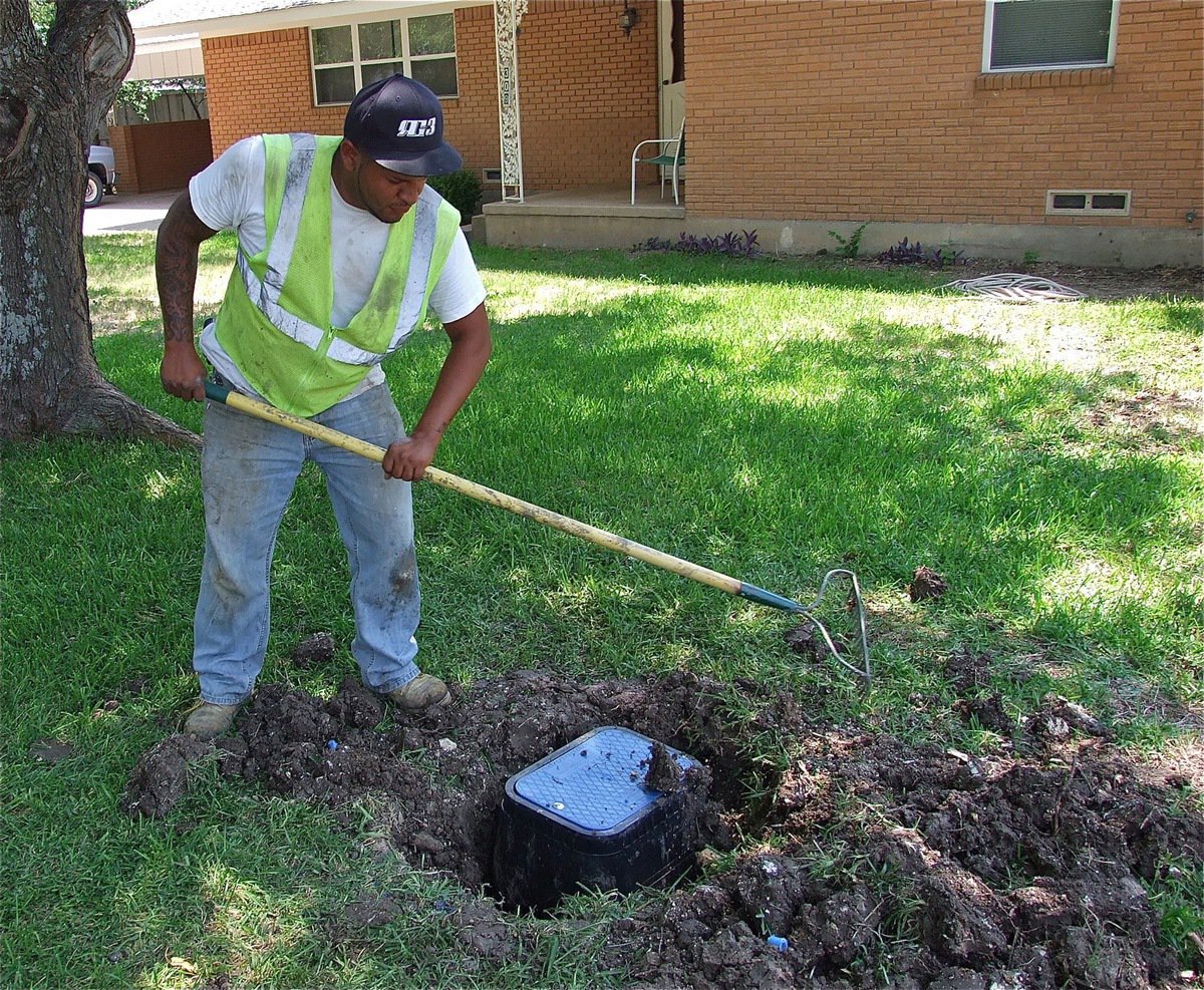 Image: Juan Carlos Gutierrez fills in the gaps surrounding a newly installed sensor controlled Smart Meter which has replaced the old drive-by meter.