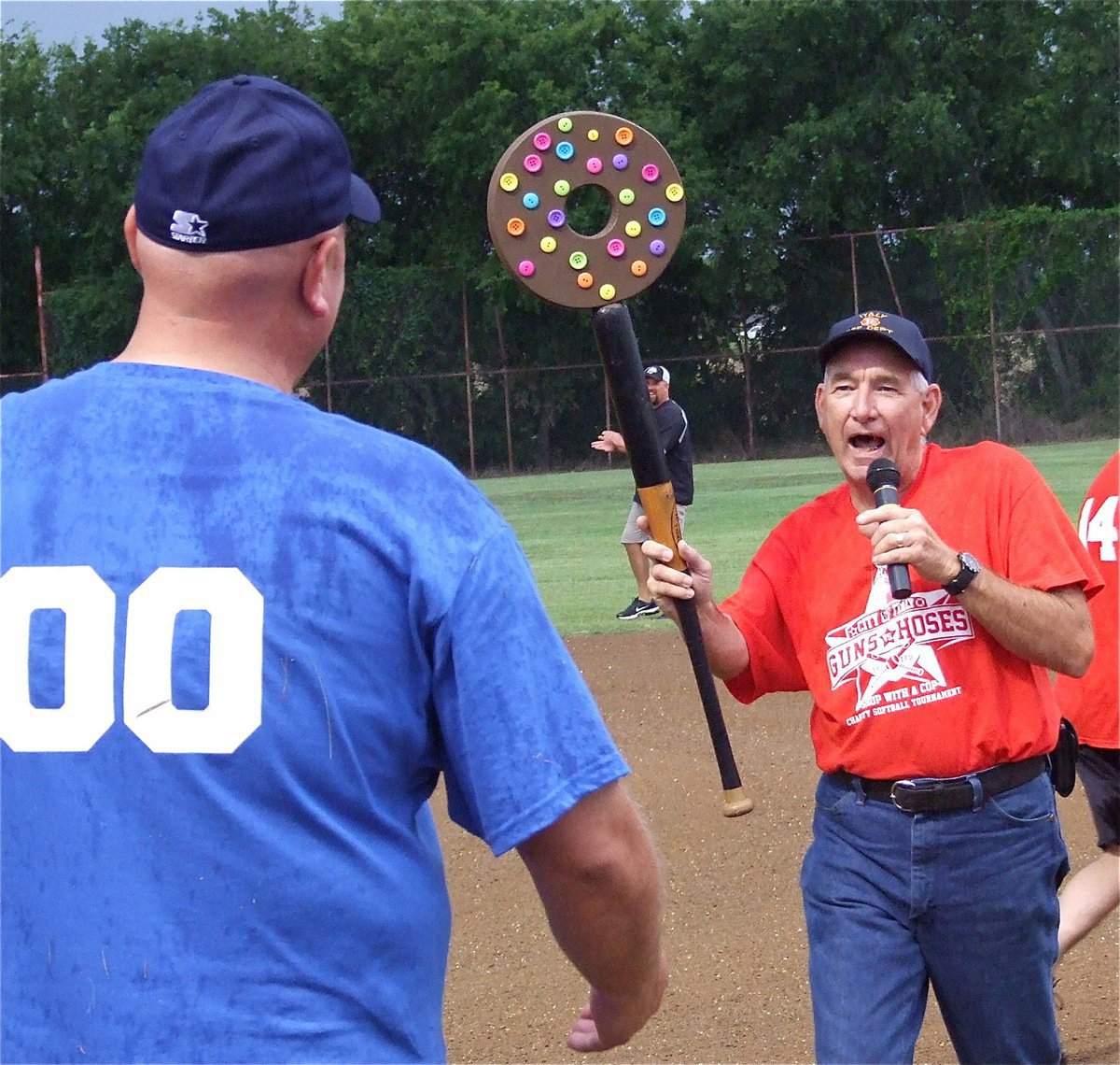 Image: I.F.D.‘s Donald Chambers offers I.P.D.’s Chief Diron Hill a police version of the firemen’s battle axe with a donut bat topped with sprinkles. 