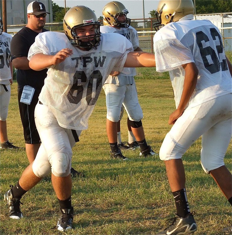 Image: Coach Brandon Duncan observes while Kevin Roldan(60), a junior, works on blocking techniques.
