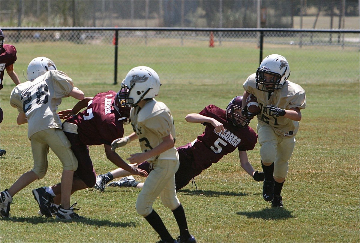 Image: IYAA A-team’s Cade Brewer(21) receives a block from Garrett Cash(28) to turn the corner.