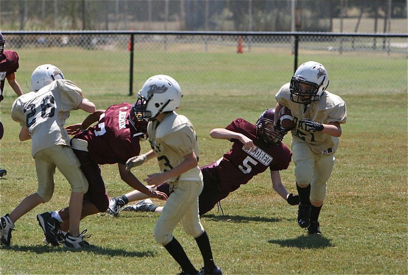 Image: IYAA A-team’s Cade Brewer(21) receives a block from Garrett Cash(28) to turn the corner.