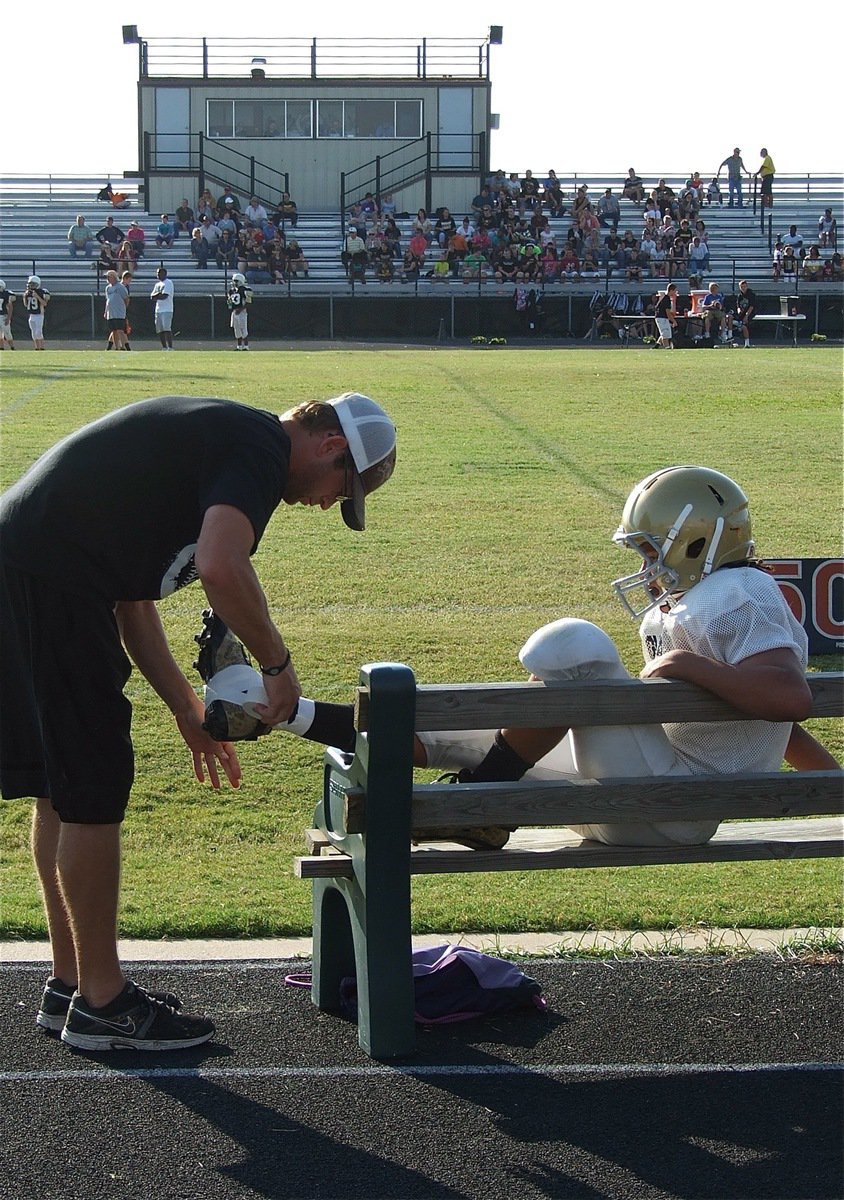 Image: Coach Nate Skelton wraps the ankle of Devonteh Williams(9).