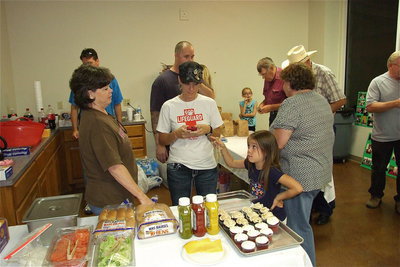 Image: Kay Chambers, Jenna Chambers (grandmother and mother) take direction from Jenna’s daughter, Morgan Chambers, who who is temporarily overseeing the chow line.