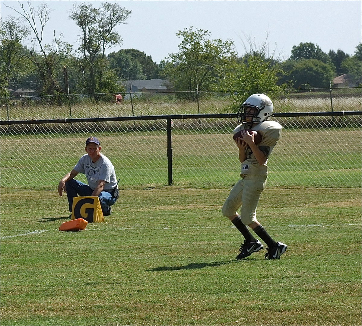 Image: Randy Boyd looks on as Miguel Martinez(33) clutches a touchdown pass to give his IYAA A-Team Gladiator squad a 12-7 lead late in the first half.