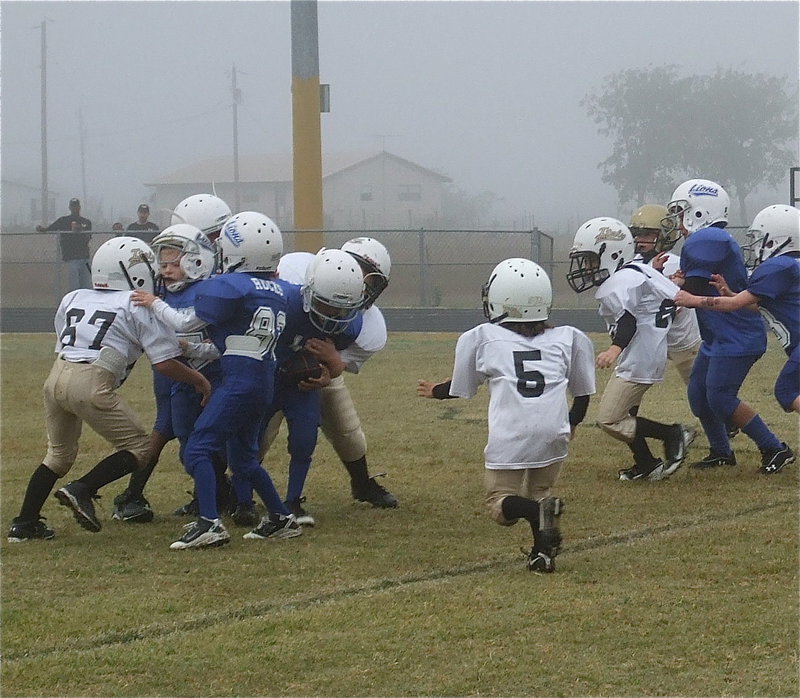 Image: Gabe Martinez(67), Bryce Ballard(98), Damien Wooldridge(5) and Kevin Magness(88) converge on a Blooming Grove runner.