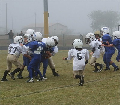 Image: Gabe Martinez(67), Bryce Ballard(98), Damien Wooldridge(5) and Kevin Magness(88) converge on a Blooming Grove runner.