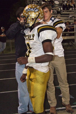 Image: Tyler Anderson and Hayden Woods(8) assist Gladiator quarterback Marvin Cox(3) with a helmet malfunction.