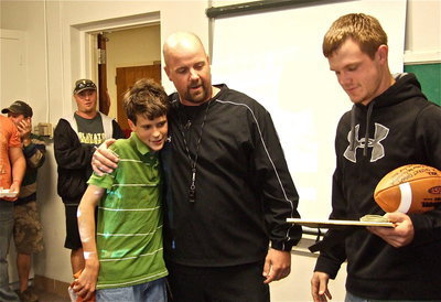 Image: Team manager and Chase Hamilton’s little brother Ty Hamilton receives a hug from Coach Hank Hollywood as the Gladiators honor their teammate and Mr. Hamilton.