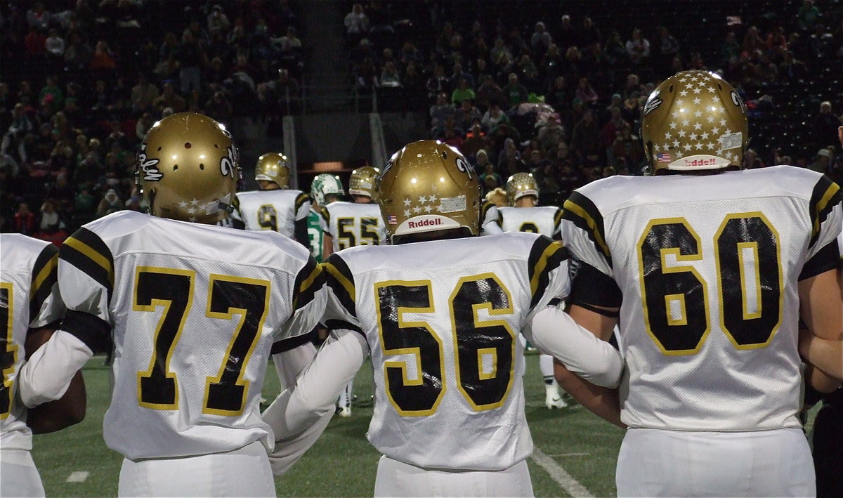 Image: Brandon Connor(77), John Escamilla(56) and Kevin Roldan(60) display unity during the coin toss.