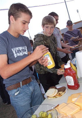 Image: Gladiator Clayton Miller looks on as Levi McBride prepares to draw a big letter “I” on each of his patties.