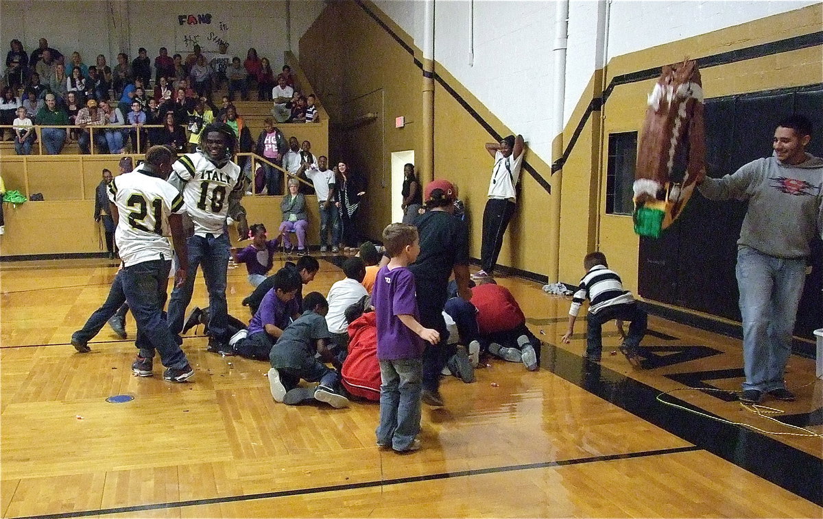Image: Jalarnce Lewis(21) and Ryheem Walker(10) retrieve candy with some of their youngest fans after teammate Zackery Boykin(55) gashed the piñata open.