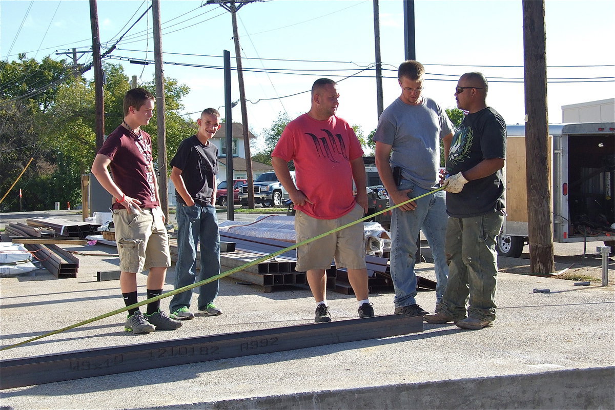 Image: Devon Bowles and Nathan Brock look on as their dad, Michael Bowles, owner of Bowles Redi Mix, Inc. of Italy, discusses the structure’s measurements with the work crew.