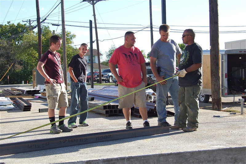 Image: Devon Bowles and Nathan Brock look on as their dad, Michael Bowles, owner of Bowles Redi Mix, Inc. of Italy, discusses the structure’s measurements with the work crew.