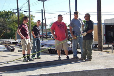 Image: Devon Bowles and Nathan Brock look on as their dad, Michael Bowles, owner of Bowles Redi Mix, Inc. of Italy, discusses the structure’s measurements with the work crew.