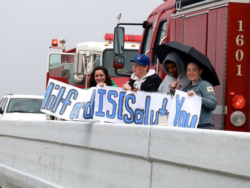 Image: Milford students display a sign that reads, “Milford ISD Salutes You,” as the Chris Kyle funeral procession passes below.