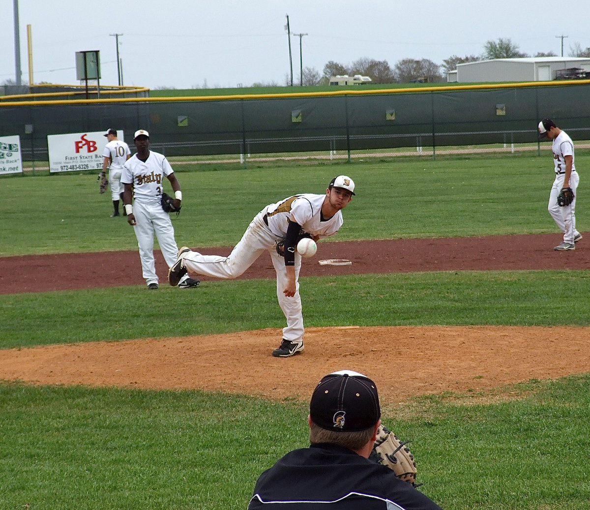 Image: Caden Jacinto(2) warms up with head coach Josh Ward between innings as Marvin Cox(3) and second baseman Reid Jacinto(5) wait for the practice throw down from catcher Ryan Connor.