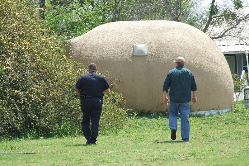 Image: Milford Police Chief Carlos Phoenix is locked and loaded during a search outside the home of David South, president of Monolithic Dome Constructors, Inc. in Italy and father of Mike South who escorts Chief Phoenix around the campus.