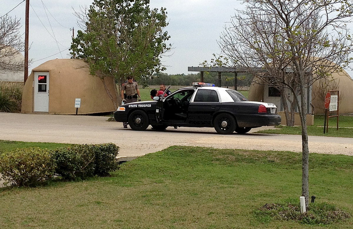 Image: Carlos Phoenix further secures the captured suspect and loads the individual into the backseat of the a State Trooper patrol car.