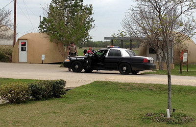 Image: Carlos Phoenix further secures the captured suspect and loads the individual into the backseat of the a State Trooper patrol car.