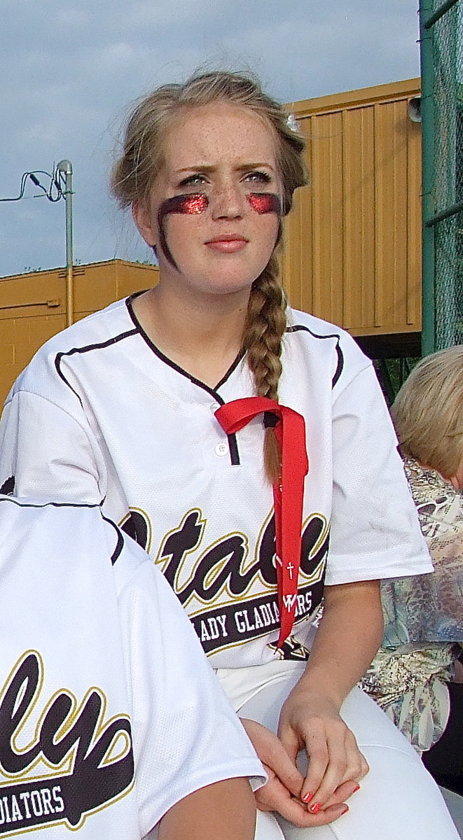 Image: Freshman Hannah Washington(8) reflects while the same clouds that passed over West and witnessed an aerial view of the destruction’s aftermath now float past the Italy Softball Field. Thursday night, the Italy Lady Gladiators kept the citizens of West in their thoughts by adding red glitter to their eye black and putting their hair up in red ribbons. Each ribbon was decorated with a cross, the date of the explosion, 4-17-13, and the initials “W.T.” for West, Texas.