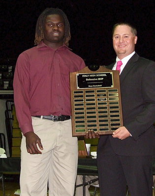 Image: Senior Ryheem Walker receives the boys Defensive MVP Award in basketball with assistant varsity basketball coach Josh Ward making the presentation.