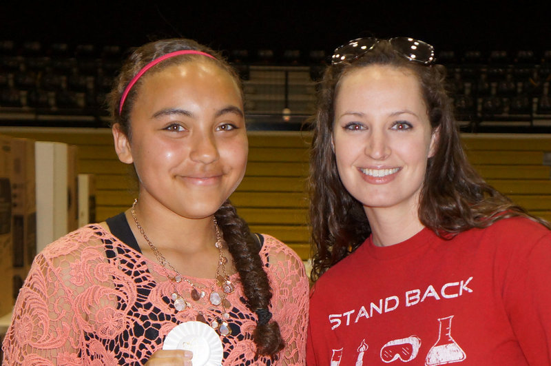 Image: Mrs. Thompson gives Vanessa the first place ribbon for the Science Fair.