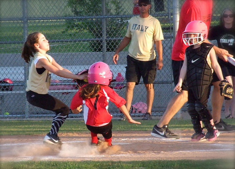 Image: With her eyes closed, and teammate Desi Miller looking on, Italy’s pitcher, Emily Janek, makes the face tag on a Waxahachie runner trying to sneak home. Despite the hustle by Janek, Waxahachie’s runner was sent back to third.