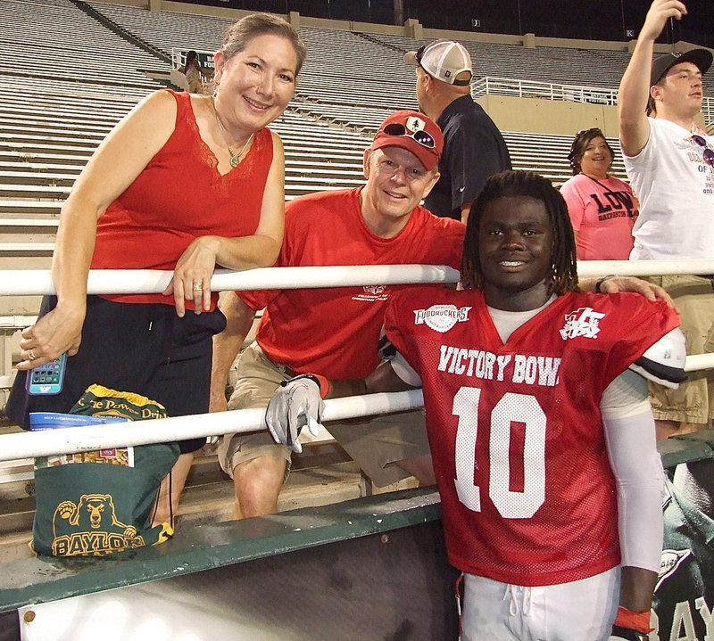 Image: Also congratulating Ryheem are Mike and Edrena Smith who were Ryheem’s host family during his three day, four night stay in Waco leading up to Victory Bowl V. “Ryheem was shy at first but he got more comfortable as the week went on. I made him talk to me,” grinned Mrs. Smith. “We had four players total staying with us and was a real joy having them in our home.” This was the second year the Smith’s to be a host family for the FCA.
