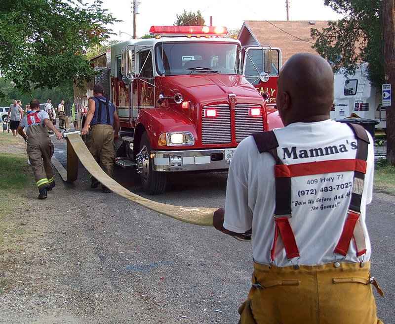 Image: Firefighters drain water from the engine hose before rolling the hose back up onto the truck.