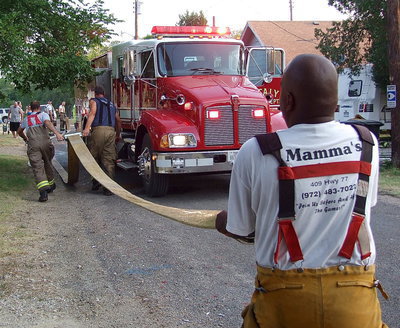 Image: Firefighters drain water from the engine hose before rolling the hose back up onto the truck.