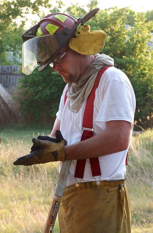 Image: Italy firefighter, Lieutenant Brad Chambers, dusts off his gloves while taking a break during the cleanup stage.