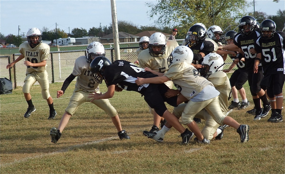 Image: Palmer fights for another inch with Italy defenders trying to pull the Bulldog runner back.