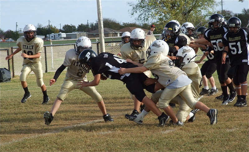 Image: Palmer fights for another inch with Italy defenders trying to pull the Bulldog runner back.
