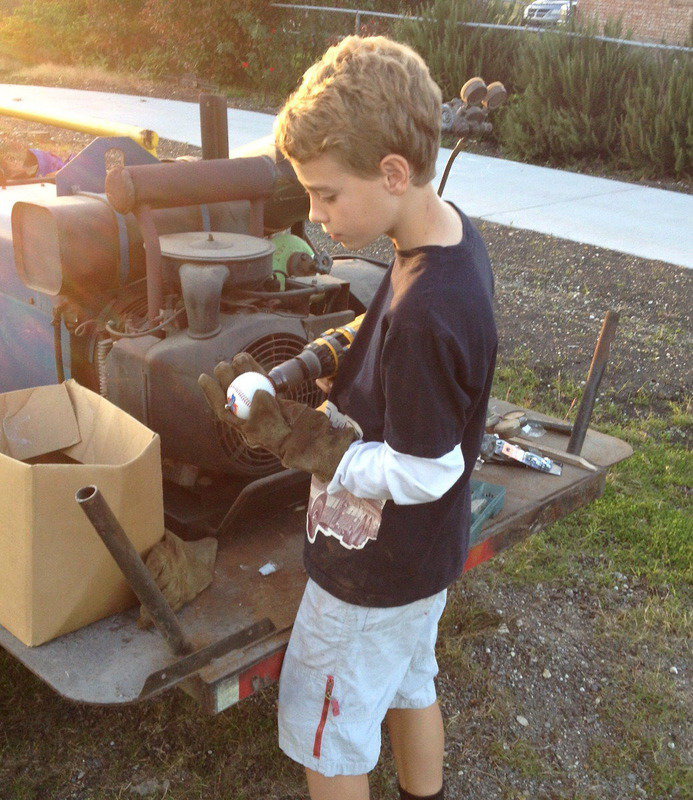 Image: Creighton Hyles drills holes thru the center of baseballs in order to pass a cable thru the core. The balls will help everyone to identify the cable wire which separates the walking trail from the parking area.