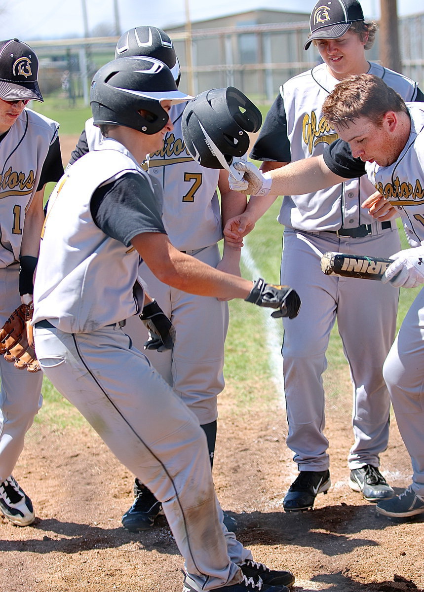 Image: Levi McBride(1) completes his home run lap with a leap onto home plate where his teammates were waiting to congratulate him.