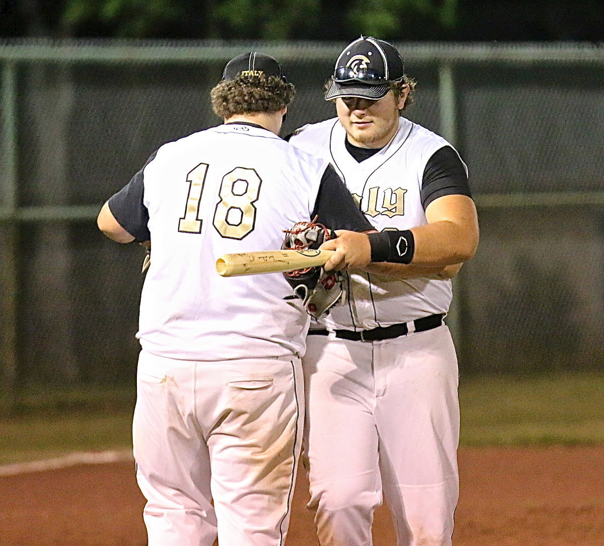Image: Gladiator senior Kevin Roldan(16) is subbed out by junior John Byers(18) as Byers presents Roldan with an engraved wooden baseball bat decorated with team signatures.