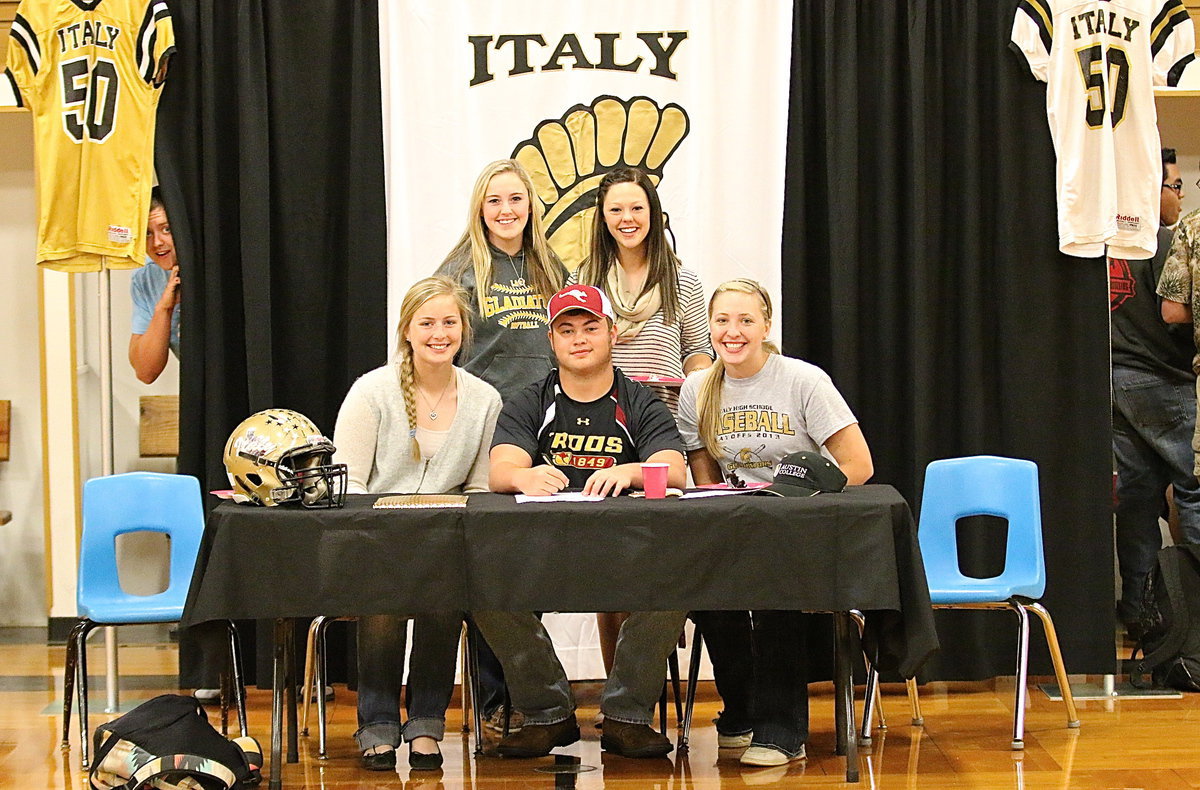 Image: Lady Gladiators Madison Washington, Kelsey Nelson, Bailey Eubank and Jaclynn Lewis umbrella Gladiator Zain Byers with support as he signs his commitment letter to play football for the Austin College Kangaroos.