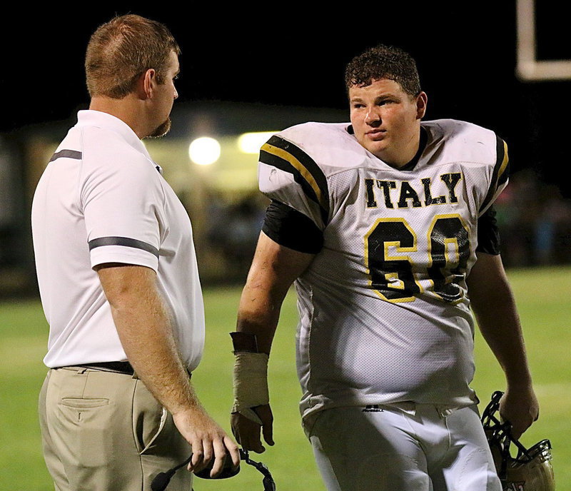 Image: Line coach Jon Proud talks shop with senior tackle John Byers(60).