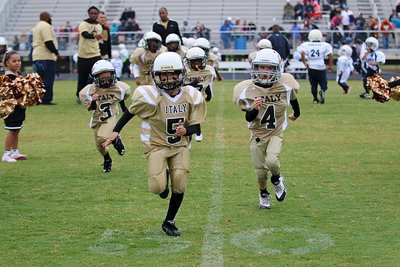 Image: Damien Wooldridge(5), Gared Wood(4), Kace McDaniel(3) lead their C-team Gladiator teammates off the field and thru spirit alley after their opening day shutout win over Rice.