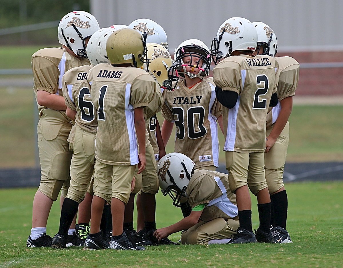 Image: B-team Gladiators huddle up to get the offensive play call from quarterback Jaylon Wallace(2).