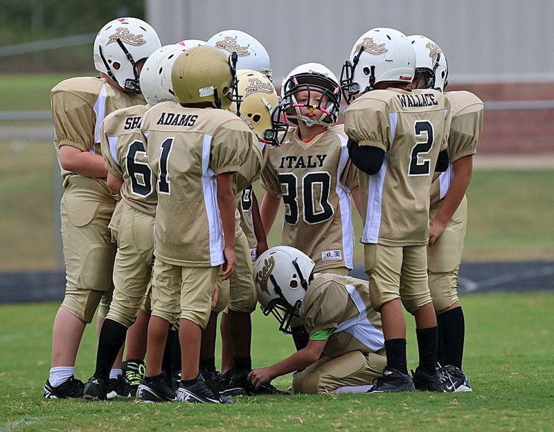 Image: B-team Gladiators huddle up to get the offensive play call from quarterback Jaylon Wallace(2).