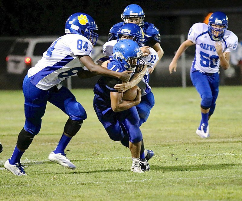 Image: Bulldog ball carrier Jaquay Brown(11) bullies his way thru a pair of Oakwood tacklers. Brown recorded 143 rushing yards on 13 carries (11.0 average) and 4 touchdowns.