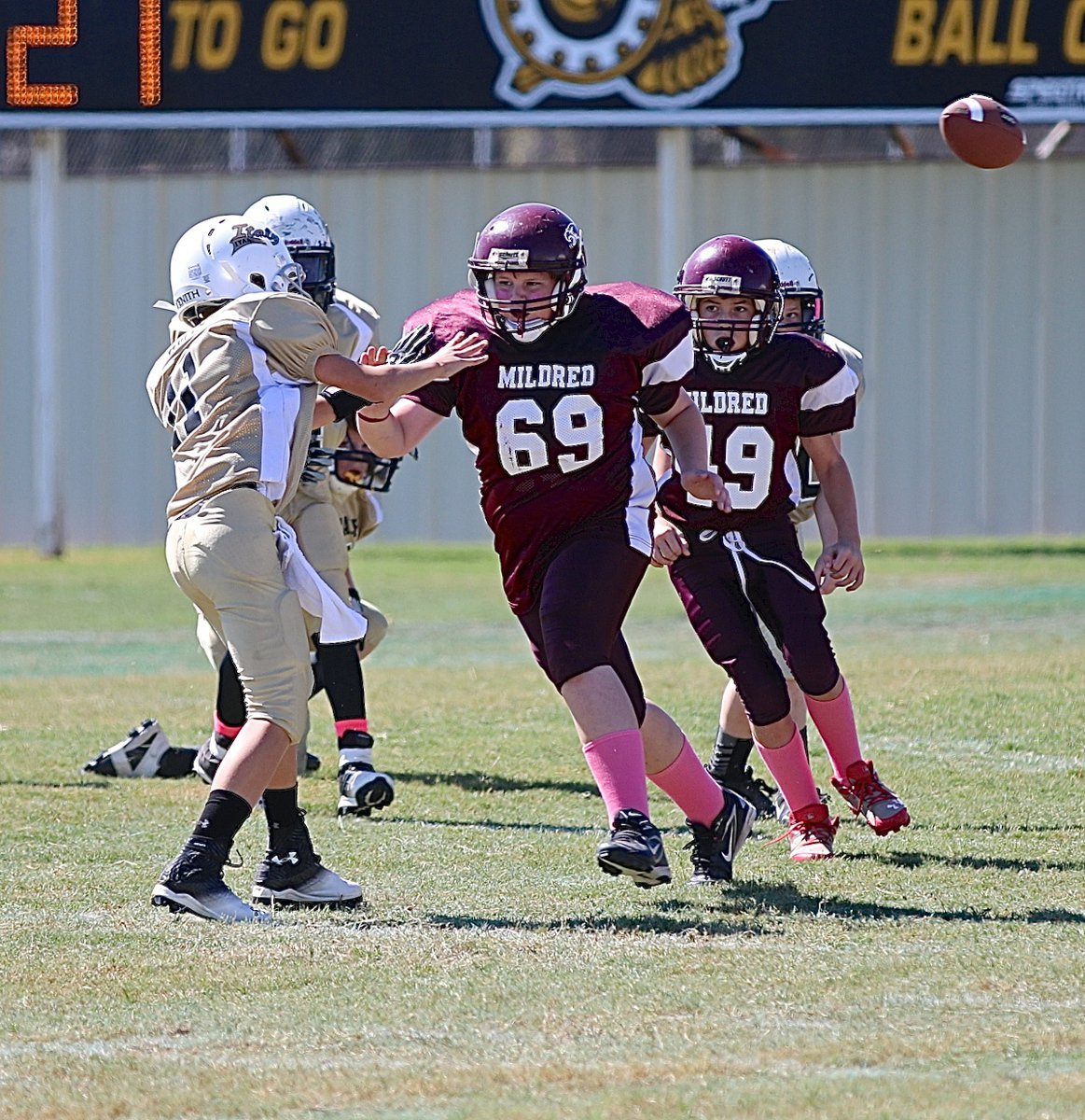 Image: IYAA A-team quarterback Creighton Hyles(11) completes a pass despite the Mildred rush in his face.