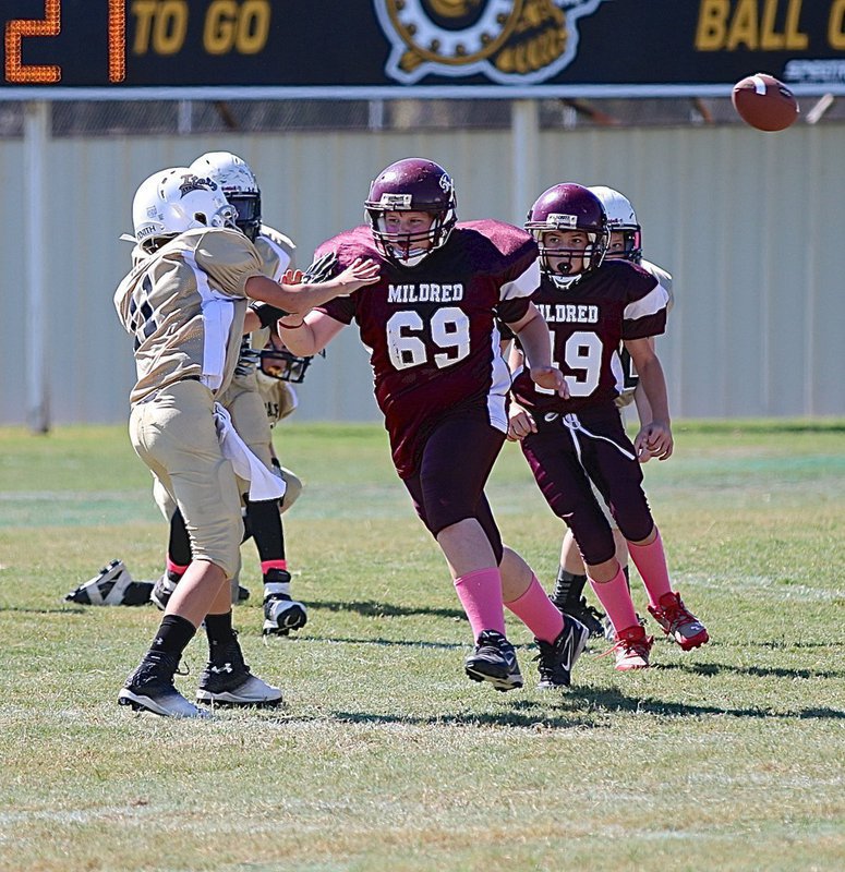 Image: IYAA A-team quarterback Creighton Hyles(11) completes a pass despite the Mildred rush in his face.